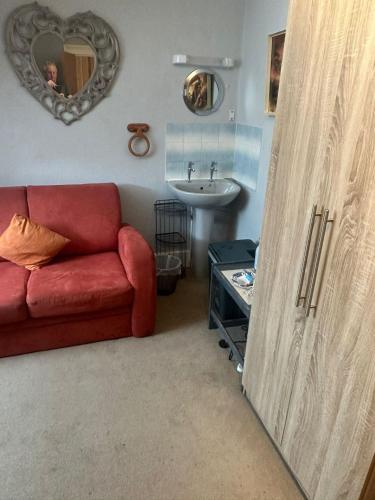 a living room with a red couch and a sink at The Barley House in Plymouth