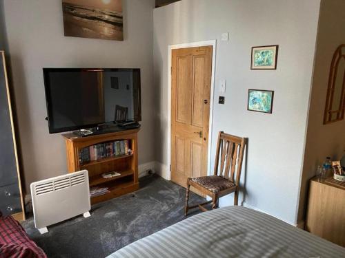 Un dormitorio con una cama, un televisor y una silla. en The Barley House, en Plymouth