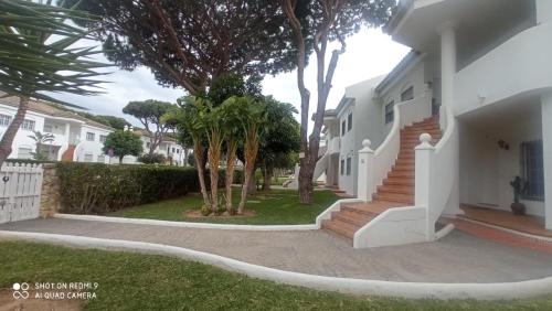 a white house with trees in the yard at Apartamento Ambar in Novo Sancti Petri