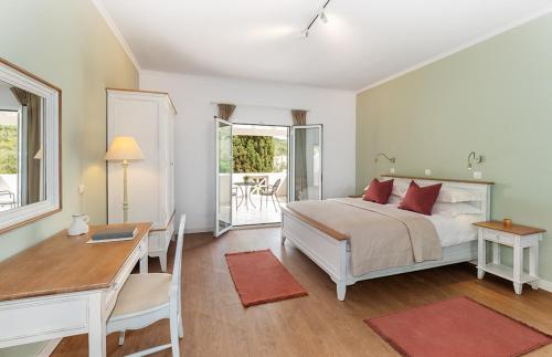 a bedroom with a bed and a desk and a table at Bella Mare Hotel in Kassiopi