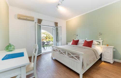 a bedroom with a bed and a desk and a balcony at Bella Mare Hotel in Kassiopi