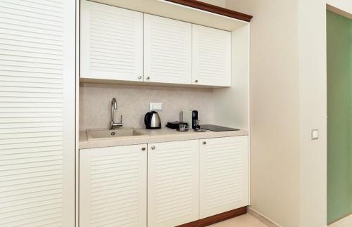 a kitchen with white cabinets and a sink at Bella Mare Hotel in Kassiopi