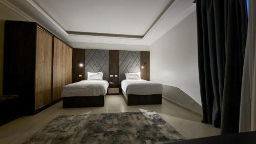 Habitación de hotel con 2 camas y alfombra en Grand Plaza 6 Octobar, en Qaryat ash Shamālī