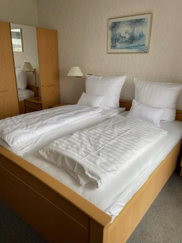 een groot wit bed met witte lakens en kussens bij La Bella in Garrel