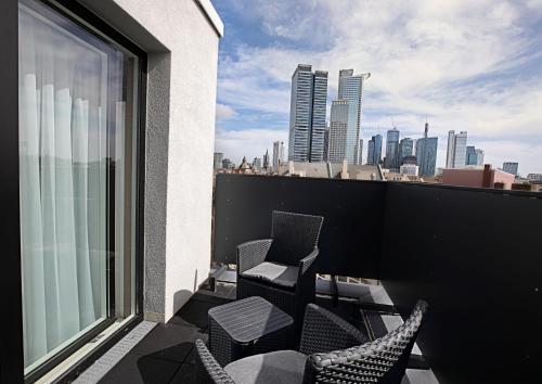 einen Balkon mit Stühlen und Stadtblick in der Unterkunft Skyline Hotel City Frankfurt in Frankfurt am Main