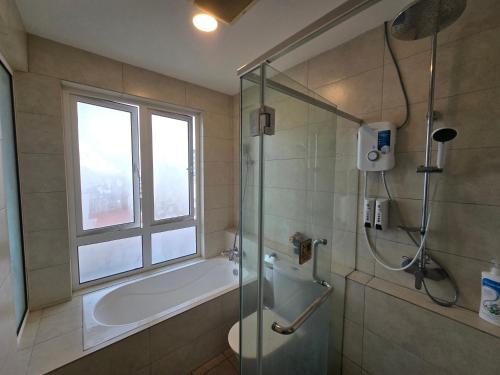 a bathroom with a shower and a tub and a window at The Octagon Ipoh City Centre Leisure Suite in Ipoh