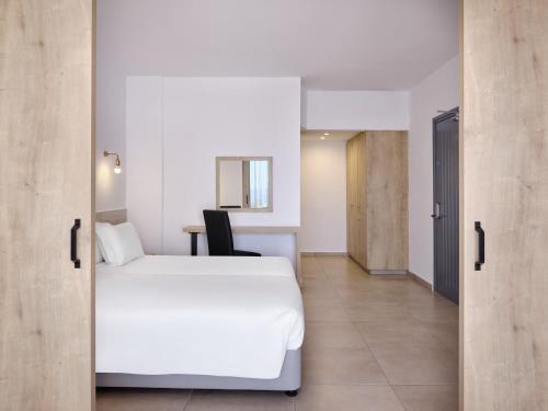 a hotel room with a white bed and a desk at Atlantica Panthea Resort in Ayia Napa
