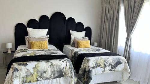 a bedroom with two beds and a large headboard at Stronoff Stays in Lobamba