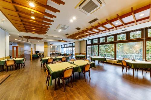 a dining room with tables and chairs and windows at 田沢湖水沢温泉郷セルリアンリゾートAoni in Senboku