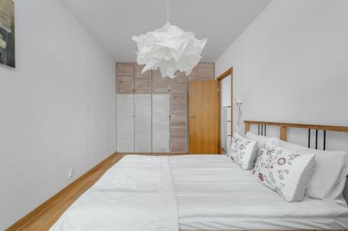 - une chambre dotée d'un lit avec des draps blancs et un lustre dans l'établissement Beautiful Apartment in Wrocław for 4 people by Rent like home, à Wrocław