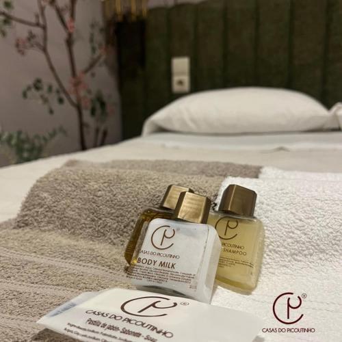 two bottles of body mist sitting on top of a bed at Casas do Picoutinho in Ponte de Lima