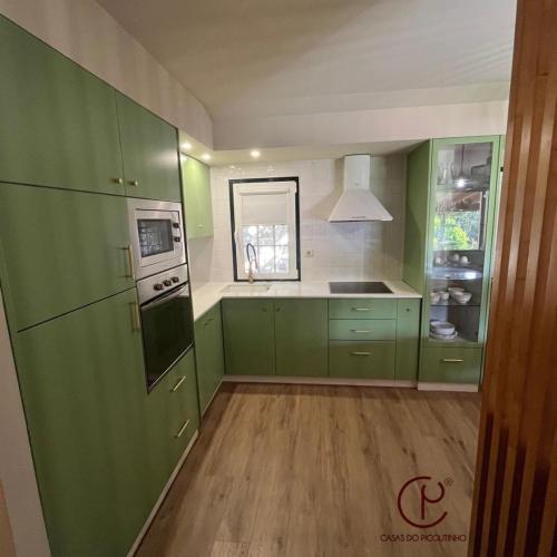 a green kitchen with green cabinets and a sink at Casas do Picoutinho in Ponte de Lima
