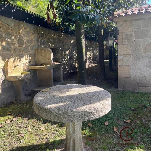 a stone bench in a garden with a tree at Casas do Picoutinho in Ponte de Lima