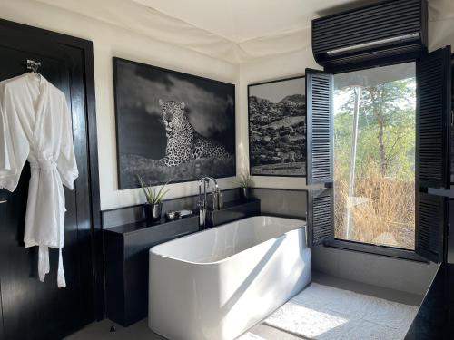 a bathroom with a white tub and a leopard picture at SUJÁN JAWAI - Relais & Chateaux in Pāli