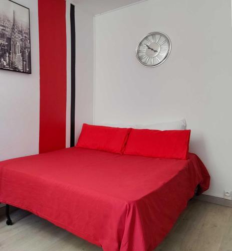 - un lit rouge dans une chambre avec une horloge sur le mur dans l'établissement Mon petit nid à Amélie, à Amélie-les-Bains-Palalda