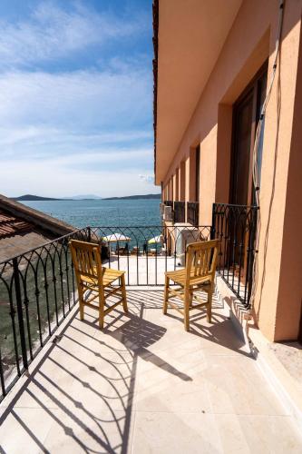 two chairs sitting on a balcony looking out at the ocean at CasaLyma Ayvalık in Ayvalık