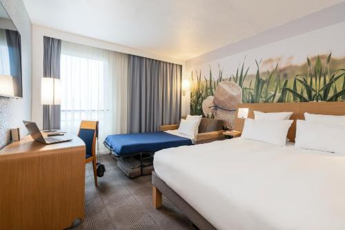 a hotel room with a bed and a desk at Novotel Paris Est in Bagnolet