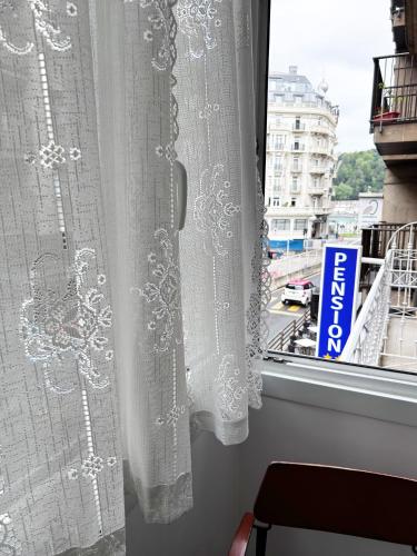 a window with white curtains and a view of a city at Pensión Régil in Donostia-San Sebastián