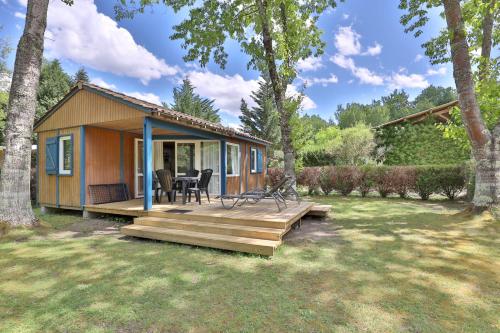 a small cabin with a wooden deck in a yard at Camping L'Etang D'Ardy *** in Saint-Paul-lès-Dax