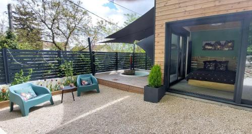 - une terrasse avec 2 chaises et un lit dans un bâtiment dans l'établissement Le Jardin des Ecureuils, à Dijon