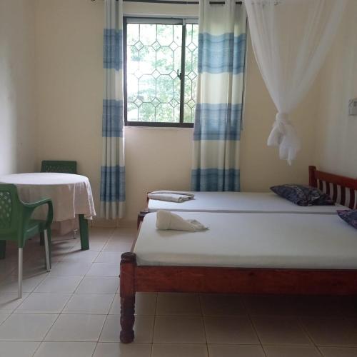 a room with two beds and a table and a window at Zaradise Suites in Mombasa