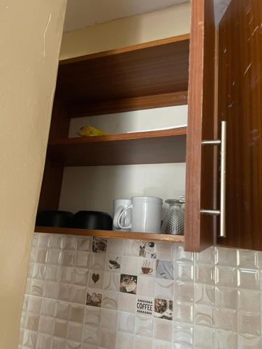 a kitchen cabinet with some cups and dishes on it at Paradise Apartments in Kilifi