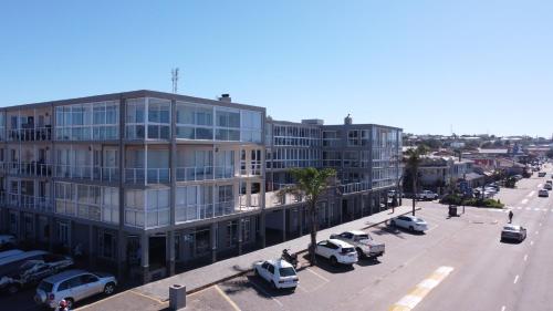 ein großes Gebäude mit auf einem Parkplatz geparkten Autos in der Unterkunft Coastal Getaway in Jeffreys Bay