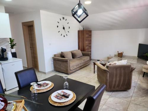 a living room with a table and chairs and a clock at Apartman Gold lux in Surčin
