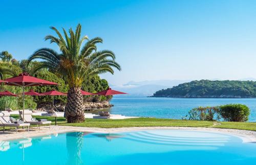 una piscina con sillas y sombrillas y el océano en Bella Mare Hotel, en Kassiopi