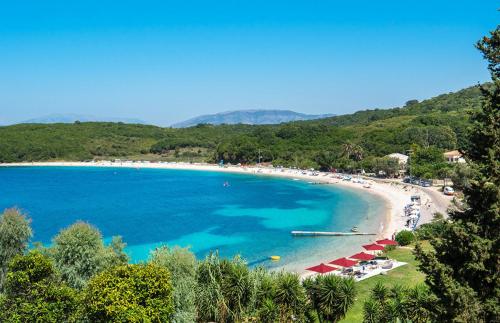 a view of a beach with red chairs and the ocean at Bella Mare Hotel in Kassiopi
