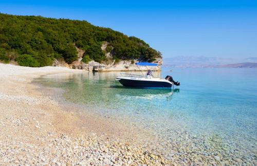a small boat in the water on a beach at Bella Mare Hotel in Kassiopi
