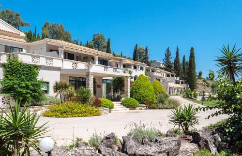 a large white house with trees and plants at Bella Mare Hotel in Kassiopi