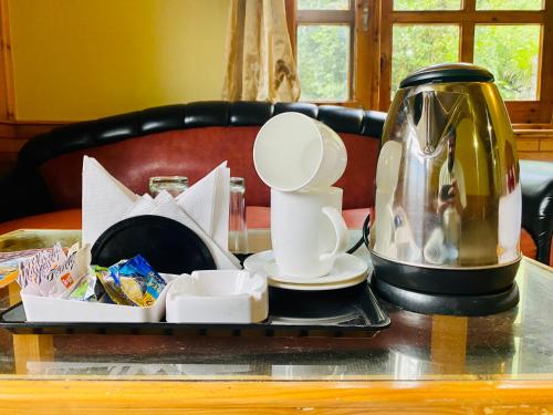 a tray with a tea kettle and cups on a table at Snow Clad Riverview Hotel & Resort, Manali in Manāli