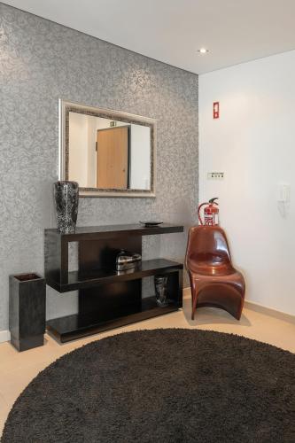 a living room with a mirror and a leather chair at Nazaré Beach House in Nazaré