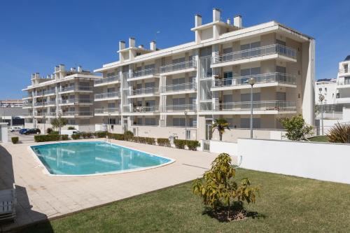 an apartment building with a swimming pool in front of it at Nazaré Beach House in Nazaré