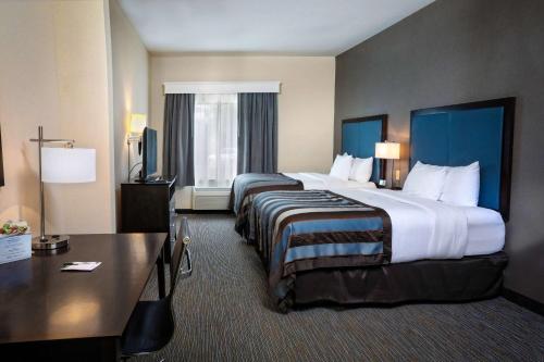 a hotel room with two beds and a desk at Wingate by Wyndham Savannah Pooler in Savannah