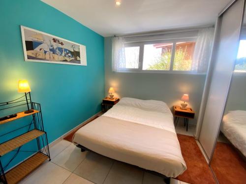 1 dormitorio con paredes azules y 1 cama con 2 lámparas en Aux pieds des pistes 4/6 personnes en Gérardmer