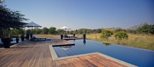 a swimming pool with two benches and an umbrella at SUJÁN JAWAI - Relais & Chateaux in Pāli