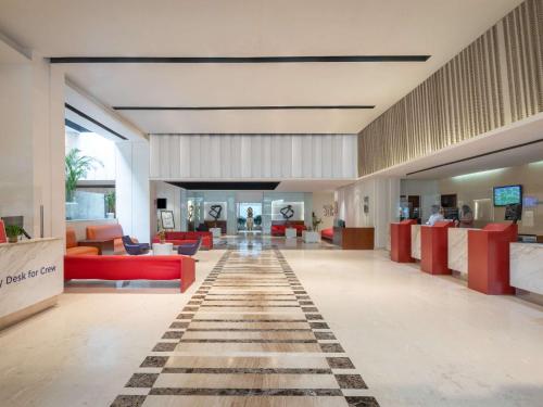 新德里的住宿－ibis New Delhi Aerocity - An Accor Brand，大堂设有红色家具和 ⁇ 板地板