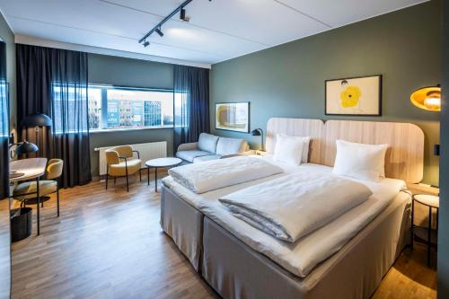コペンハーゲンにあるスカンディック シューハウネンのベッドルーム(大型ベッド1台付)、リビングルームが備わります。