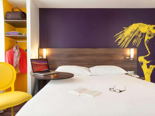 1 dormitorio con cama con ordenador portátil y libro en ibis Styles Saumur Gare Centre, en Saumur