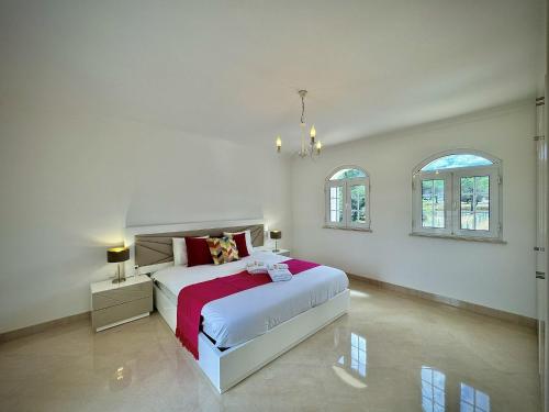 a white bedroom with a bed and two windows at Quarteira Premium Villa With Pool by Homing in Quarteira