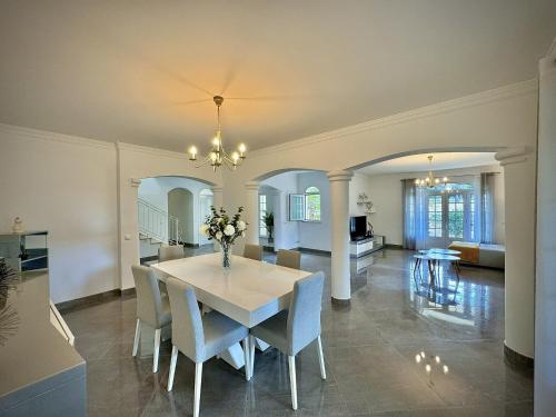 a dining room with a white table and chairs at Quarteira Premium Villa With Pool by Homing in Quarteira