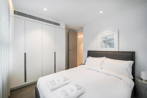a bedroom with a white bed and white cabinets at The Shore 7 Coogee Beach in Sydney