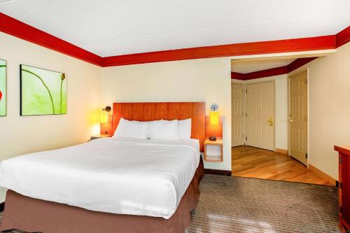 a hotel room with a large bed and a door at La Quinta by Wyndham Raleigh/Durham Southpoint in Durham