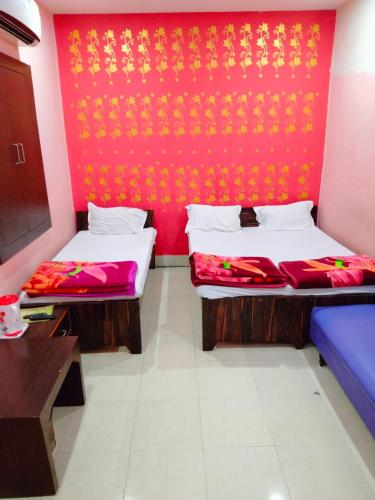 2 camas en una habitación con una pared roja en Hotel Atithi Galaxy en Kānpur