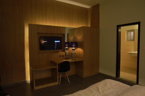 a bedroom with a bed and a desk with a television at Sunset BnB in Karachi
