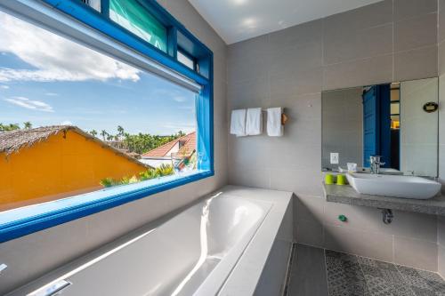 een badkamer met een bad, een wastafel en een raam bij Chez Mimosa Rice Farm Hoi An - New address DX18, Thanh Nhut, Cam Thanh in Hội An