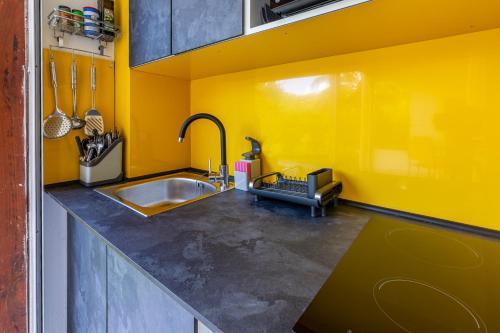 a kitchen with a sink and a yellow wall at Le Kanmpo in Trois-Îlets