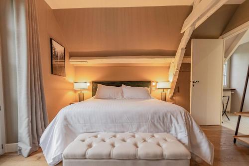 a bedroom with a large bed with a white bedspread at Le Moulin de l'Ortille & SPA in Compiègne